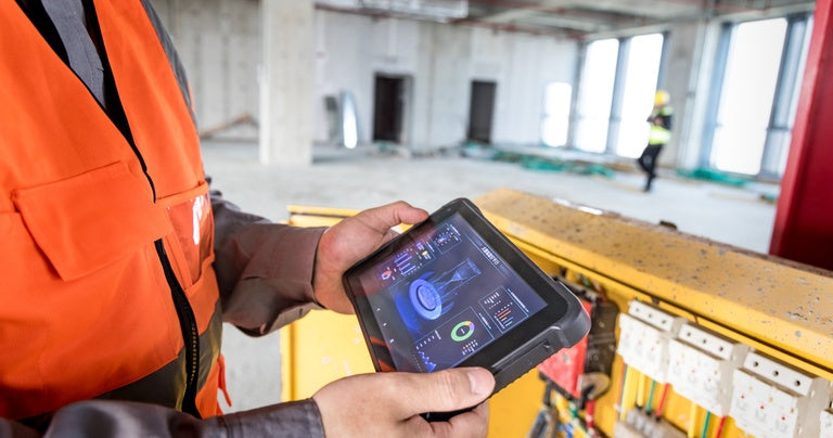 Construction engineer using a rugged tablet for site inspection, project monitoring and field data collection.