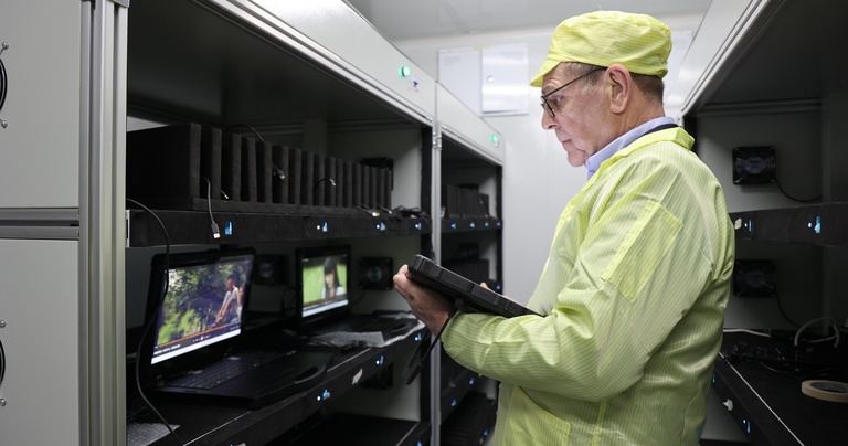 Industrial engineer inspecting factory equipment with a rugged tablet for maintenance and production management.