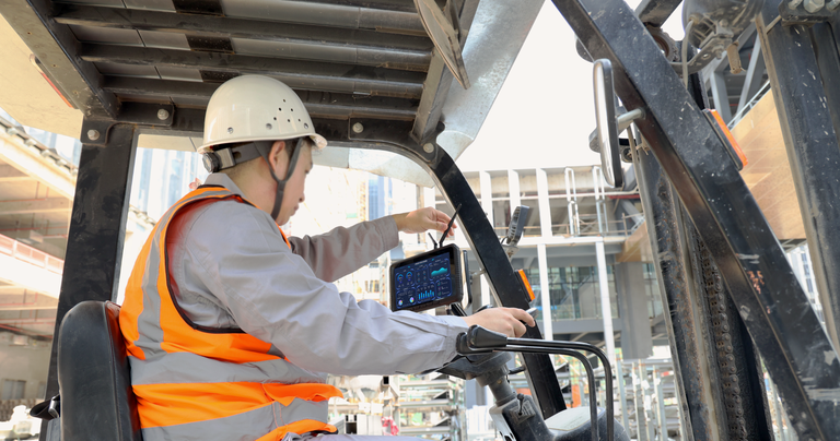 Technician installing a rugged forklift mounted tablet inside a forklift for warehouse and industrial operations.