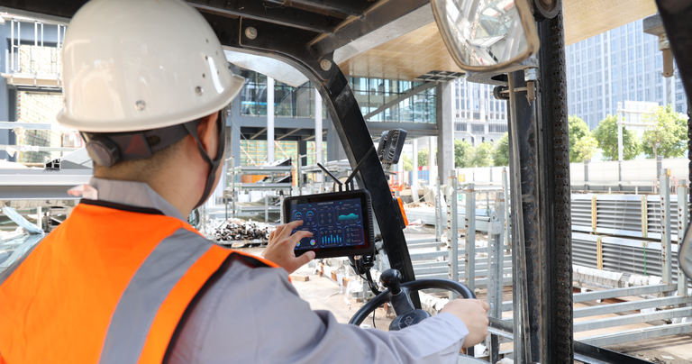 Forklift operator using a rugged tablet mounted inside the forklift for warehouse inventory management.
