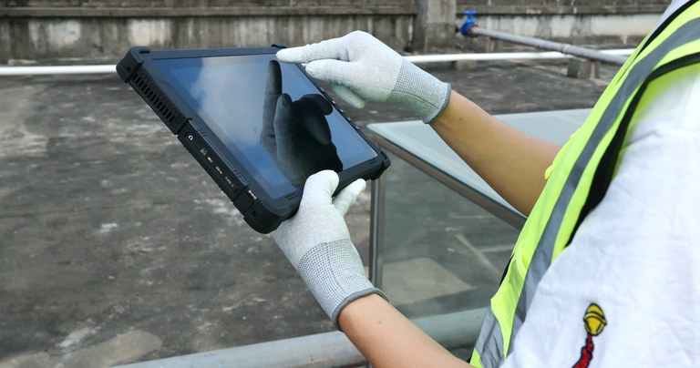 Worker using a rugged construction tablet with gloves in an outdoor work environment