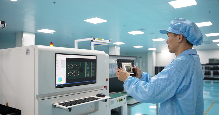 Industrial engineer using an Arrvel rugged tablet for electronics manufacturing quality inspection on a PCB production line.