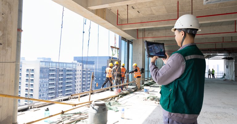 Worker using a rugged tablet for construction site inspection and project monitoring